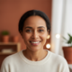 Close-up portrait of a smiling woman in her 40s with clear, healthy skin, looking directly at the camera.